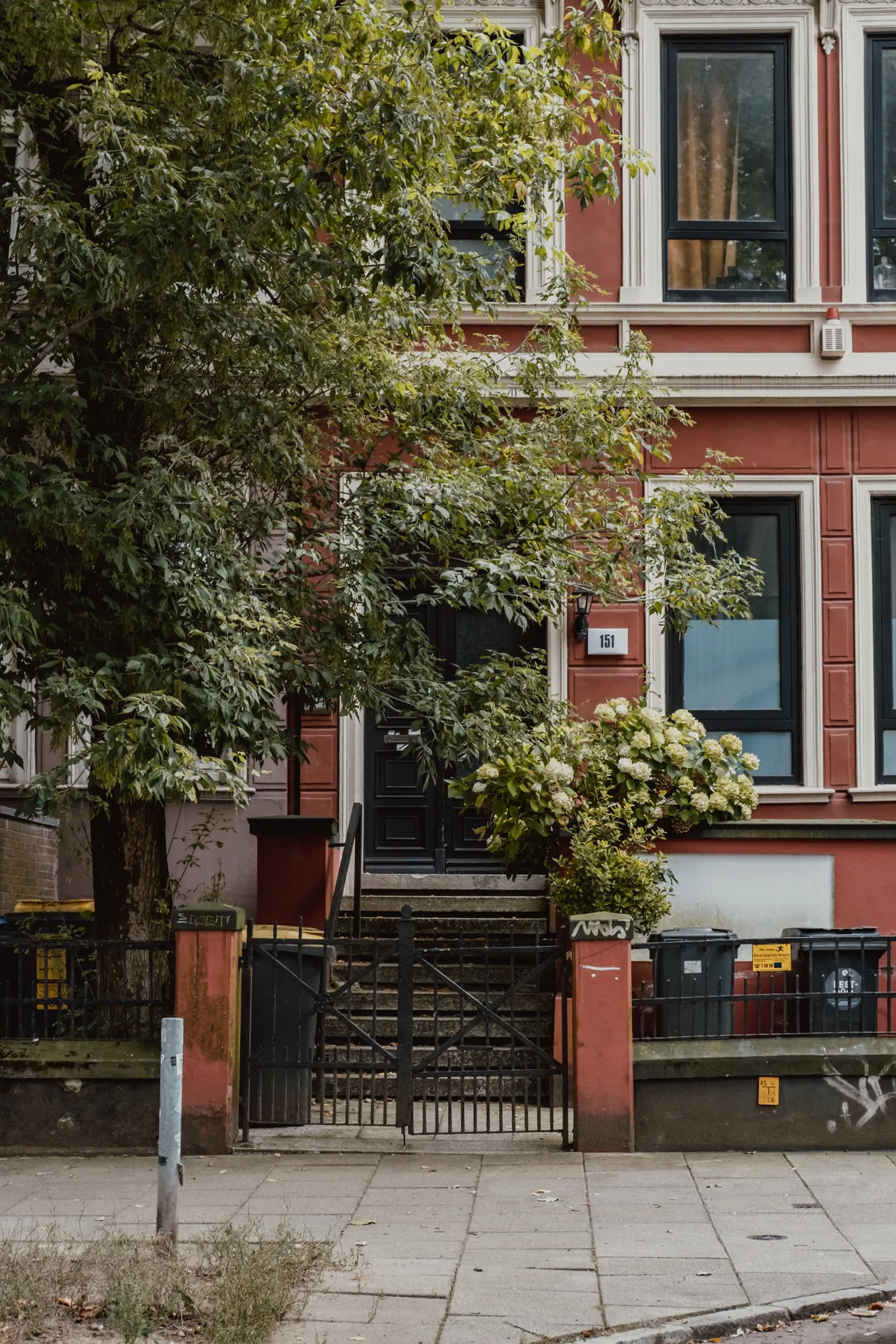 Leafy residential building with a red facade